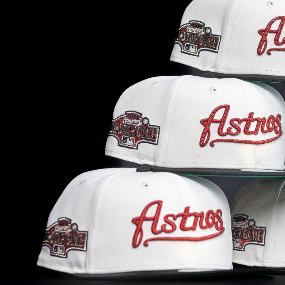 A stack of Red Soda New Era HOF Red Black Chrome Houston Astros 5950 Fitted hats, each featuring a red embroidered Astros logo and a Houston All-Star Game patch, set against a black background.