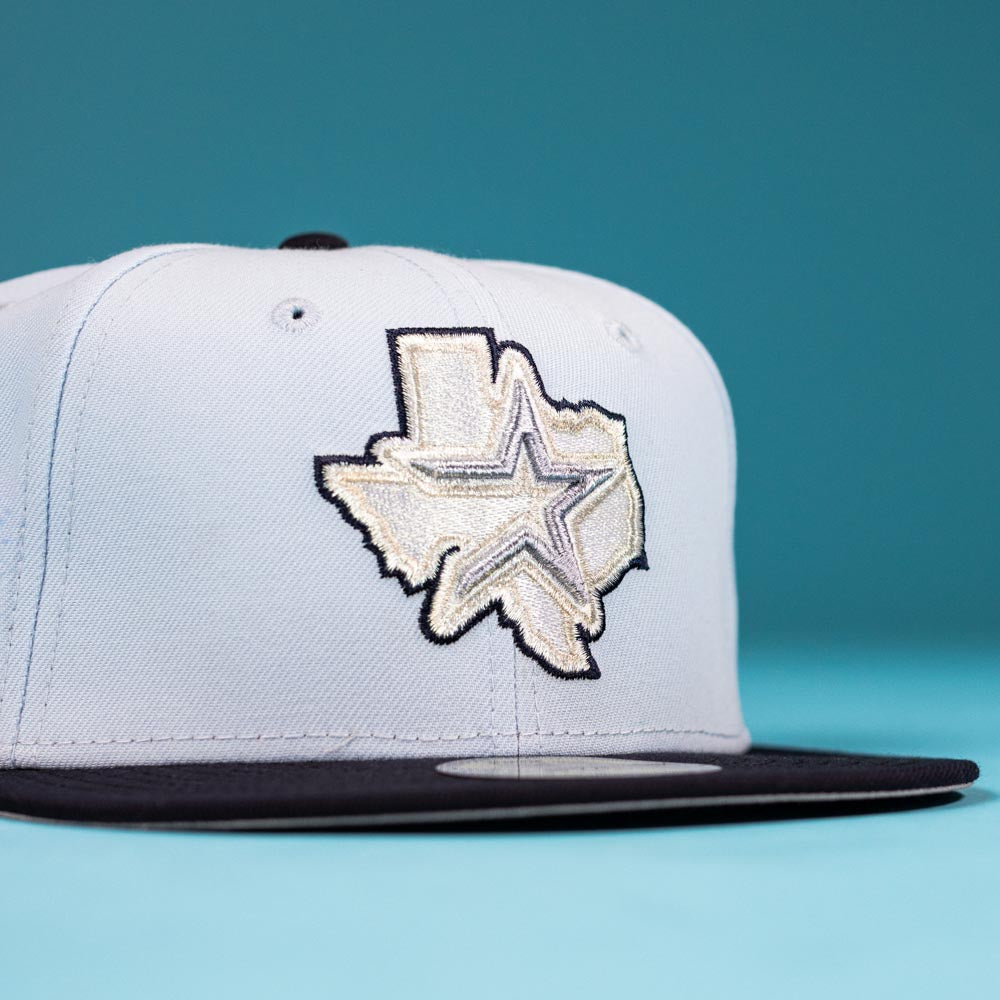 The Hard Freeze WS05 Houston Astros New Era Hat 5950 Fitted is a light gray snapback with a black brim, featuring an embroidered Texas outline and star, inspired by the iconic Astros fitted hat, shown on a bold blue background.