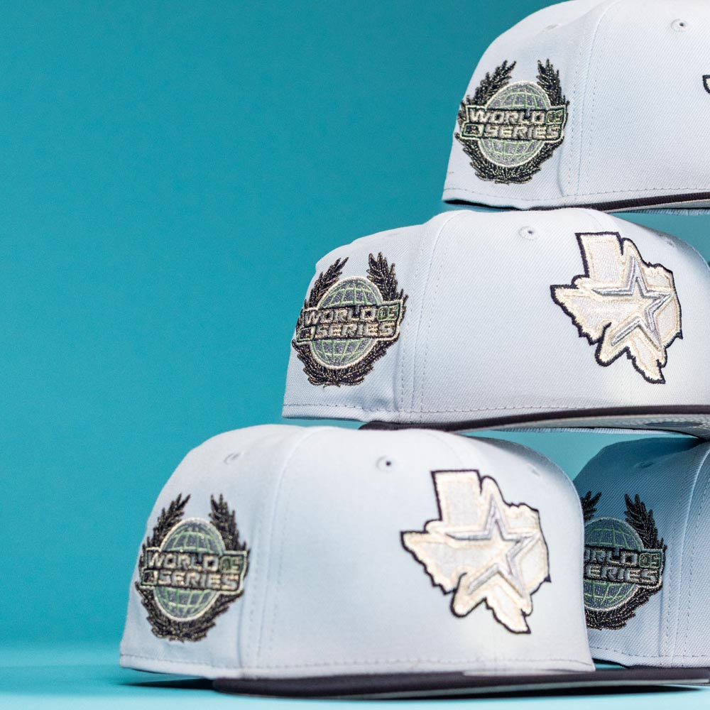 Four Hard Freeze WS05 Houston Astros New Era Hat 5950 Fitted hats, each with World Series patches and a Texas state outline with a star, stacked on a blue background—ideal for passionate Houston Astros fans.