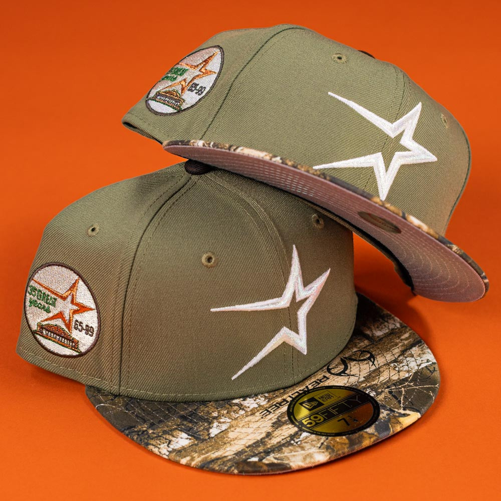 Two Pre-Order Wall Hanger New Era Bark Real Tree Houston Astros 5950 Fitted hats with camouflage brims, white star logo, and SOTG Special 65-89 patch are displayed on an orange background. Pre-order now with flexible shipping options.