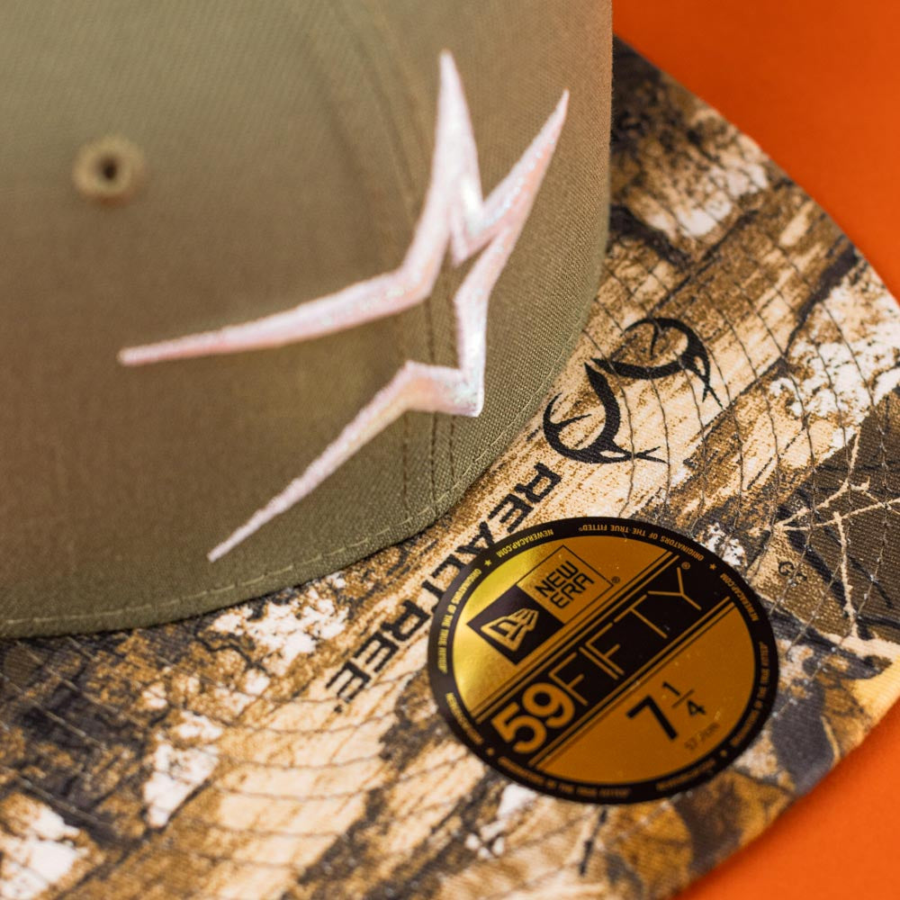 The Pre-Order Wall Hanger New Era Bark Real Tree Houston Astros 5950 Fitted hat features a khaki crown, white star logo, camo brim with "REALTREE," gold size 7 1/4 sticker, and comes with convenient shipping. Orange background included.