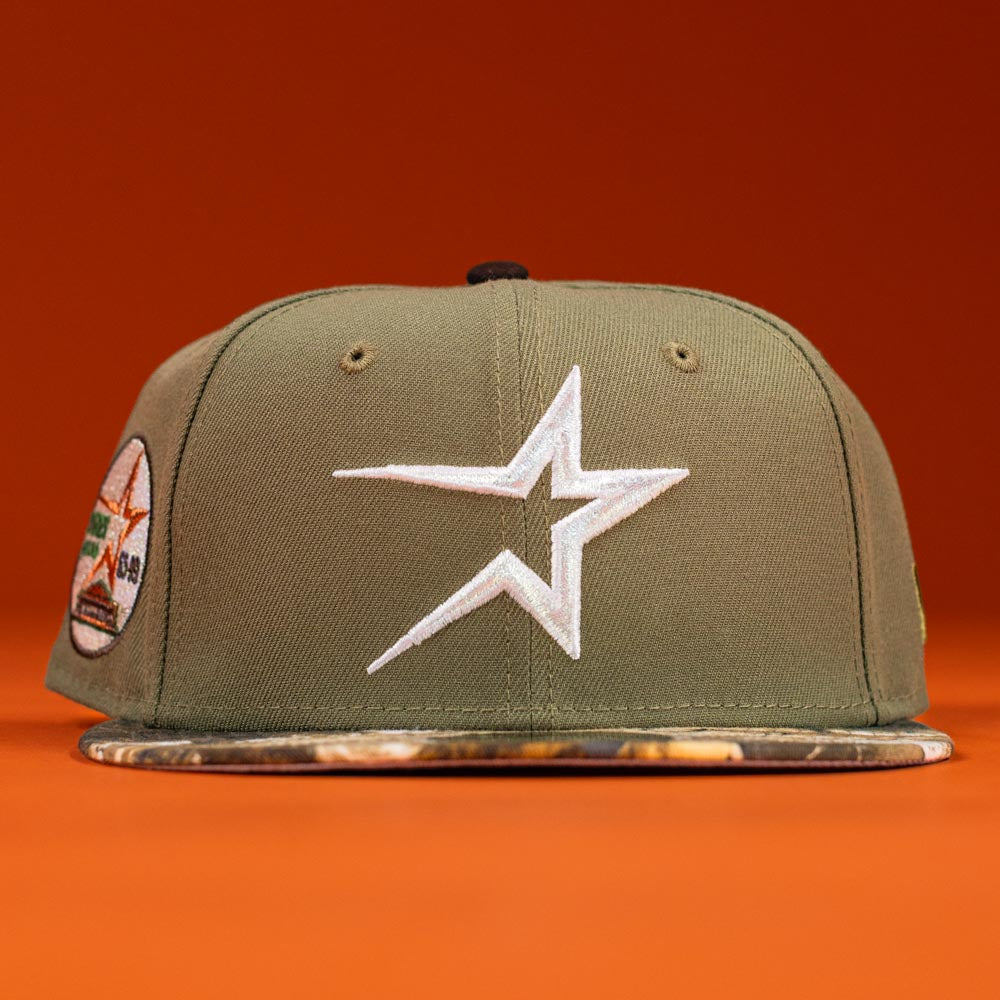 The Pre-Order Wall Hanger New Era Bark Real Tree Houston Astros 5950 Fitted hat features an olive green snapback, white star logo, camouflage brim, and side patch on an orange background. Pre-order now with flexible shipping options.