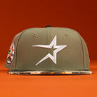 The Pre-Order Wall Hanger New Era Bark Real Tree Houston Astros 5950 Fitted hat features an olive green snapback, white star logo, camouflage brim, and side patch on an orange background. Pre-order now with flexible shipping options.