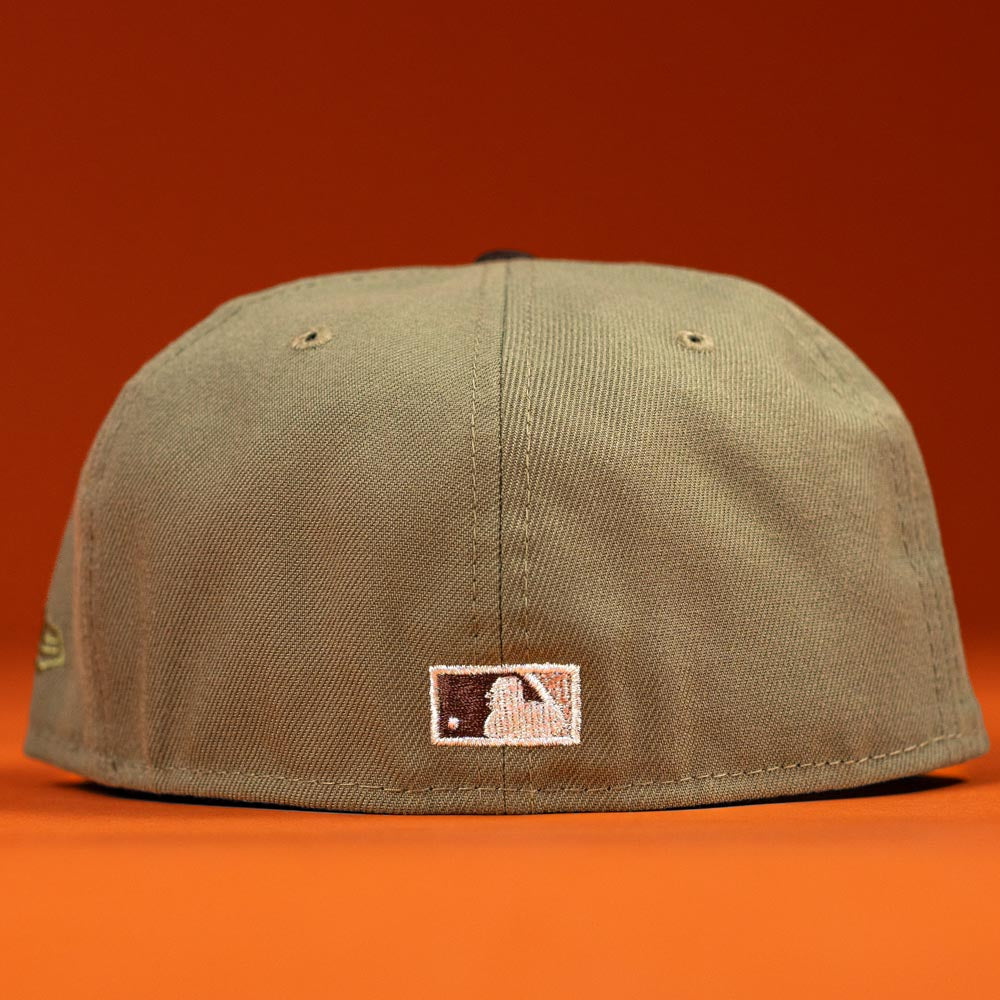 A Wall Hanger New Era Bark Real Tree Houston Astros 5950 Fitted Hat is shown from the back with a white and black MLB logo against an orange background. Pre-order now to enjoy convenient shipping options for your purchase.