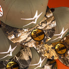 A stack of Pre-Order Wall Hanger New Era Bark Real Tree Houston Astros 5950 Fitted hats with camo brims, white embroidered logos, and gold "59FIFTY 7 1/2" stickers—available for pre-order or in-store pick-up.