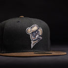 The Midnight Cowboy Sugarland Space Cowboys New Era 5950 Fitted Hat is black with a brown brim and features an embroidered cowboy logo in a hat and scarf on the front, set against a dark background.