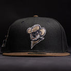 The Midnight Cowboy Sugarland Space Cowboys New Era 5950 Fitted Hat features a black walnut cap with a brown brim and an embroidered Space Cowboys logo—a cowboy in a hat and bandana—on the front, set against a dark background.