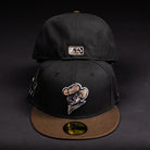 Two Midnight Cowboy Sugarland Space Cowboys New Era Hat 5950 Fitted caps are shown: one forward with the team logo, and one backward revealing a small patch. Both hats have flat brims and Black Walnut coloring.