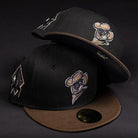 Two Midnight Cowboy Sugarland Space Cowboys New Era 5950 Fitted hats, in black walnut and brown with embroidered cowboy and arrow designs, are stacked on a dark background, adding signature Space Cowboys style.