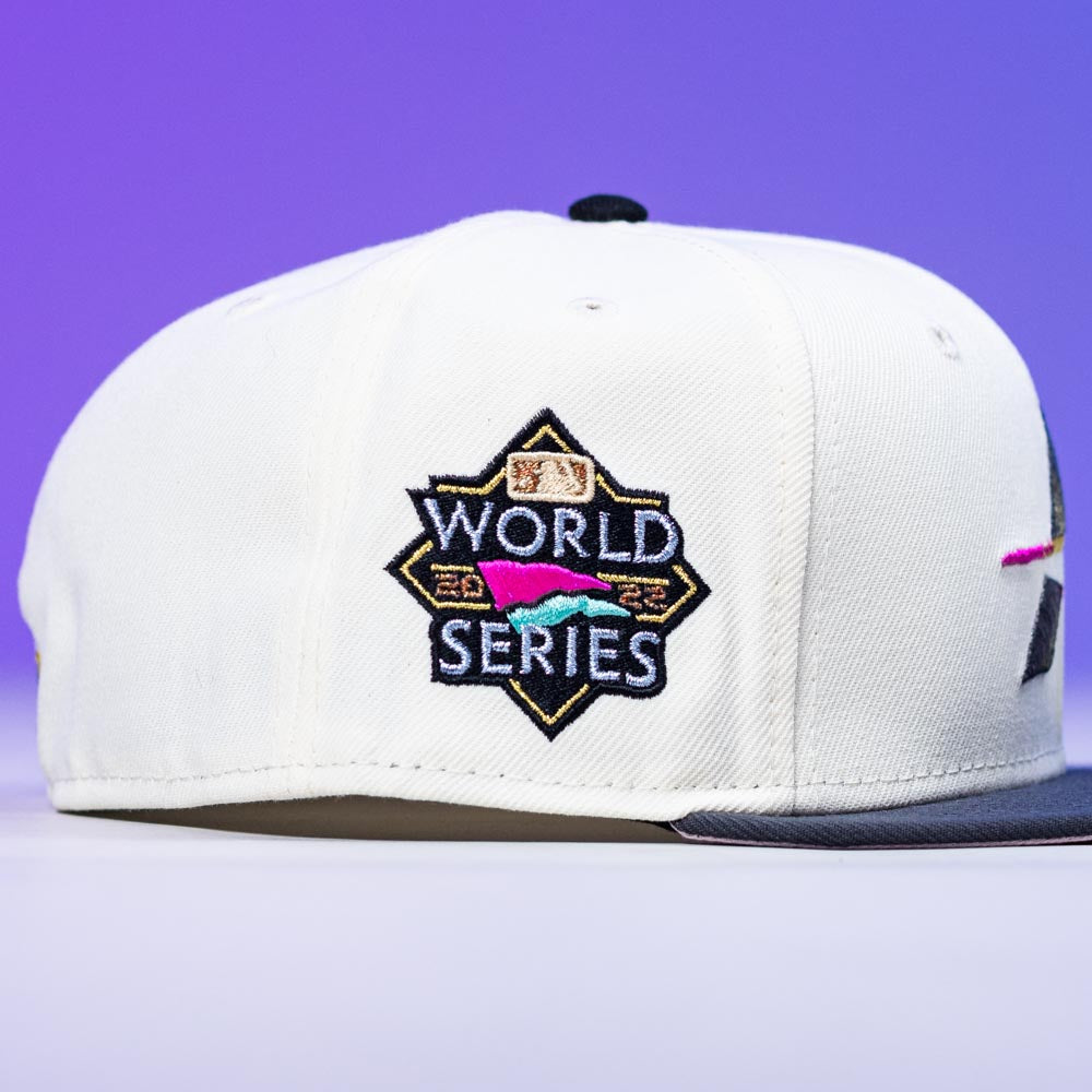 The Trilltiberi Rushmore WS22 Chrome Graphite Houston Astros New Era 5950 Fitted Hat features a black brim and colorful World Series patch, shown against a purple gradient background.