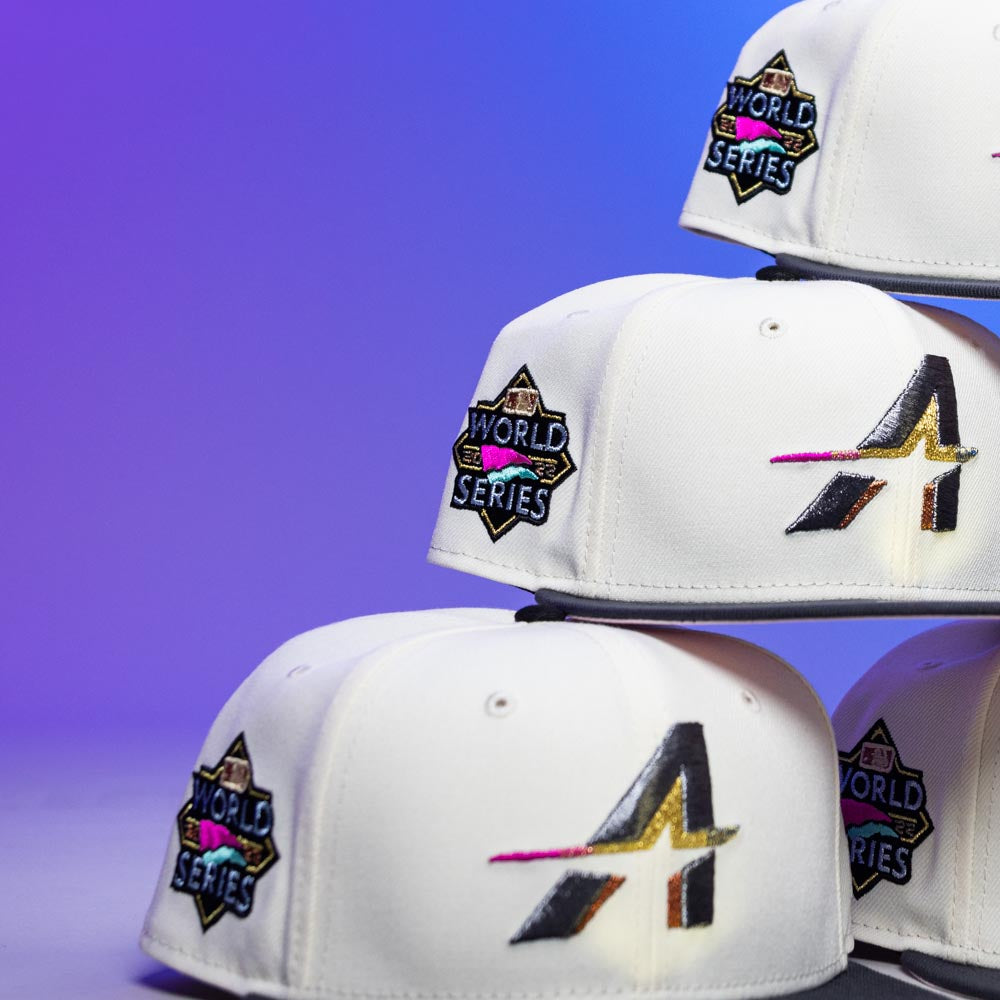 Three stacked Trilltiberi Rushmore WS22 Chrome Graphite Houston Astros New Era 5950 Fitted hats, each with the team’s logo on the front and a vibrant World Series patch on the side, set against a purple gradient background.