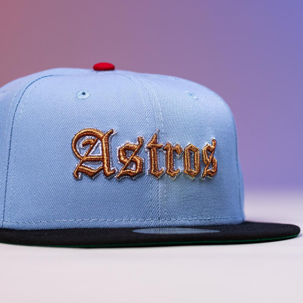 The Sicko Mode Rushmore 2017 B Blue Black Houston Astros New Era 5950 Fitted Hat features gold Astros embroidery on the front, a black brim, and red top button, set against a vibrant purple gradient background.