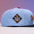 The Sicko Mode Rushmore 2017 B Blue Black Houston Astros New Era Hat 5950 Fitted features a light blue crown, black brim, red top button, and a diamond-shaped 2017 World Series patch on the side. The background displays a purple to pink gradient.
