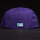 A close-up of the back of the DAY N HOU Rushmore WS05 Purple Teal Houston Astros New Era Hat 5950 Fitted shows a small rectangular MLB logo patch above the brim, set against a black background.