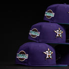 Three DAY N HOU Rushmore WS05 Purple Teal Houston Astros New Era 5950 Fitted hats, each featuring a gold star H logo and World Series patch, are stacked on a black background.