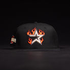 The La Flame Rushmore WS05 Fire Black Houston Astros New Era 5950 Fitted Hat features a white star with orange flames on the front, a colorful side patch, and is shown against a dark background.