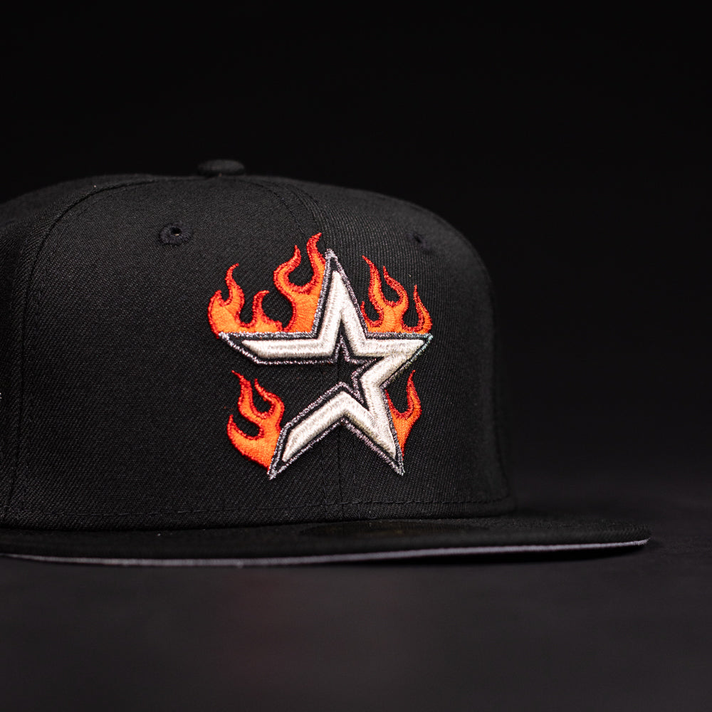The La Flame Rushmore WS05 Fire Black Houston Astros New Era Hat 5950 Fitted features an embroidered silver star outlined in black, surrounded by orange and red flames on the front, set against a dark background.