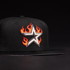 The La Flame Rushmore WS05 Fire Black Houston Astros New Era Hat 5950 Fitted features an embroidered silver star outlined in black, surrounded by orange and red flames on the front, set against a dark background.