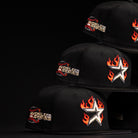 Three La Flame Rushmore WS05 Fire Black Houston Astros New Era Hat 5950 Fitted caps are stacked diagonally, each with a flaming star on the side and a World Series patch on the front, set against a sleek black background.