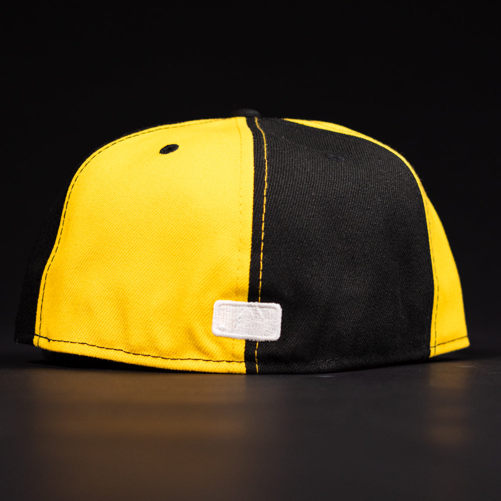 The Hazmat Rushmore Gold Black Pinwheel Houston Astros New Era Hat 5950 Fitted is shown from the back, highlighting its vertical split design and a small white rectangular tag near the bottom seam against a dark background.