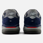 A pair of 933 LNV Navy Slate Gray Andrew Reynolds New Balance Numeric Suede Skateboarding Shoes in navy blue, gray, and red, viewed from the back with the NB logo displayed on the heels and a gray, red, and black rubber sole—these classic heritage sneakers blend timeless style with premium cushioning for all-day comfort.