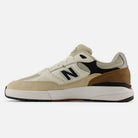 A left side profile of the 933 ONE Quicksand Sea Salt Gray Andrew Reynolds New Balance Numeric Suede Skateboarding Shoe is displayed against a white background, highlighting its heritage-inspired design in cream suede with black, tan, and white accents, and featuring premium cushioning for all-day comfort.