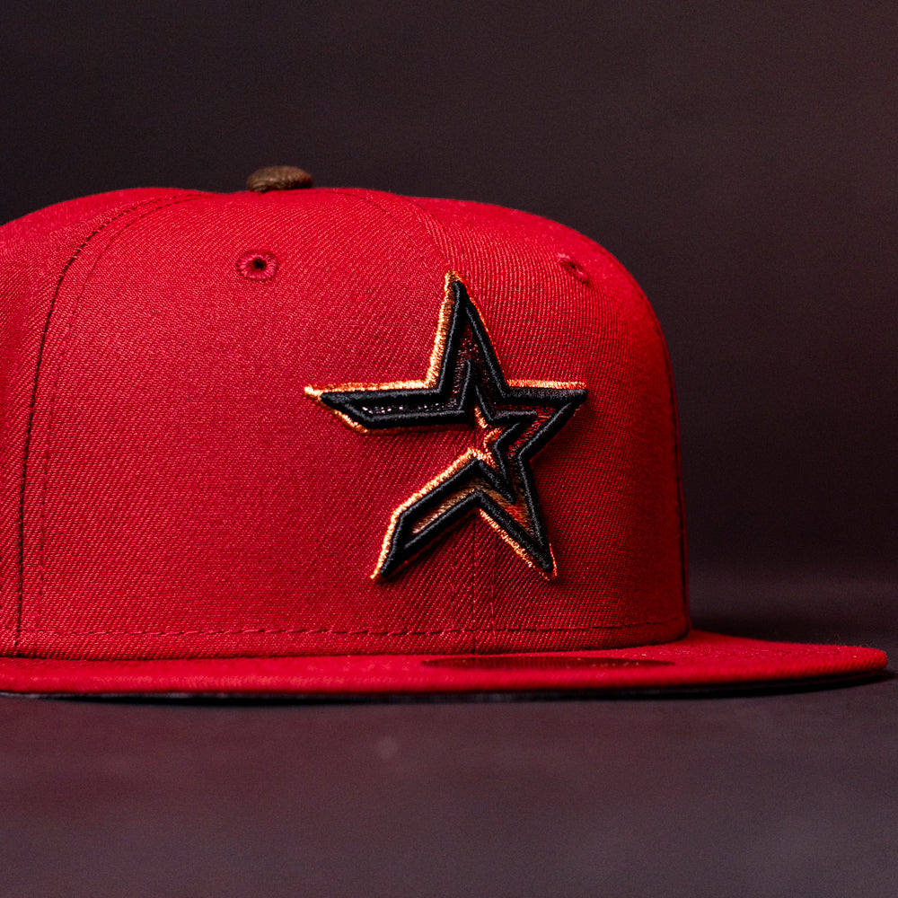 The ASG19 Bred Houston Astros New Era Hat 5950 Fitted is a red fitted cap with a black and gold embroidered star logo on the front, shown against a dark background.