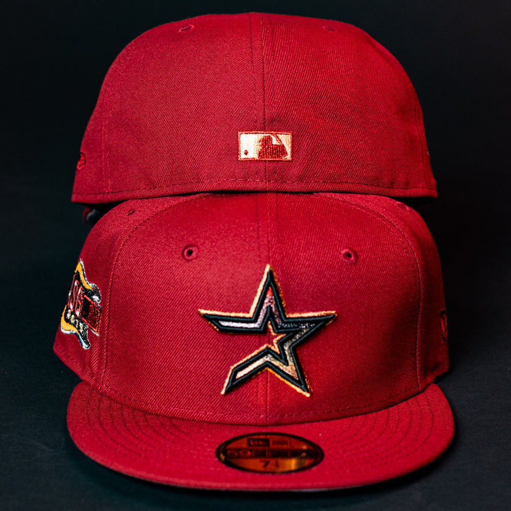 Two ASG19 Bred Houston Astros 5950 Fitted New Era hats in red, featuring black, white, and gold star logos; one shows the MLB logo on back, the other shows the front logo and a side patch.
