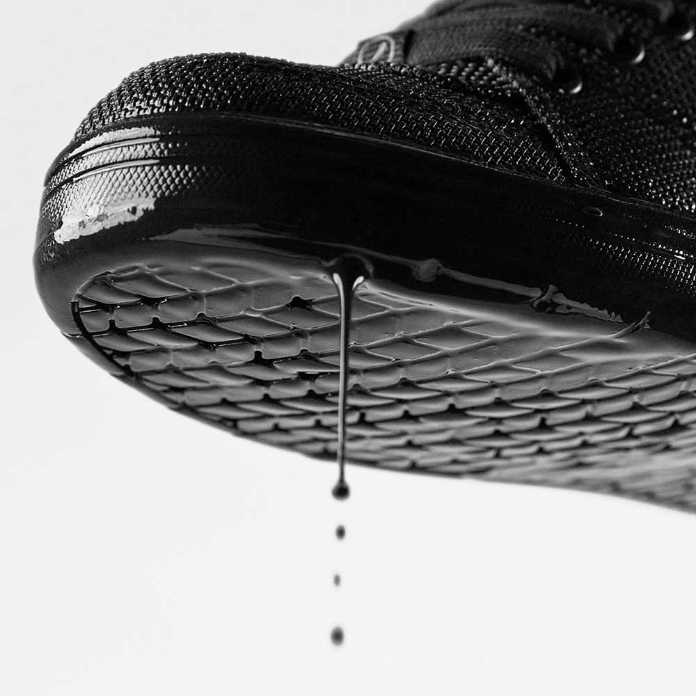 Close-up of the sole of the Accel Kevlar Black Es Shoes Skateboarding, liquid dripping off to highlight texture and wetness. The plain, light background showcases every detail—perfect for reflecting skateboarders' everyday realities.