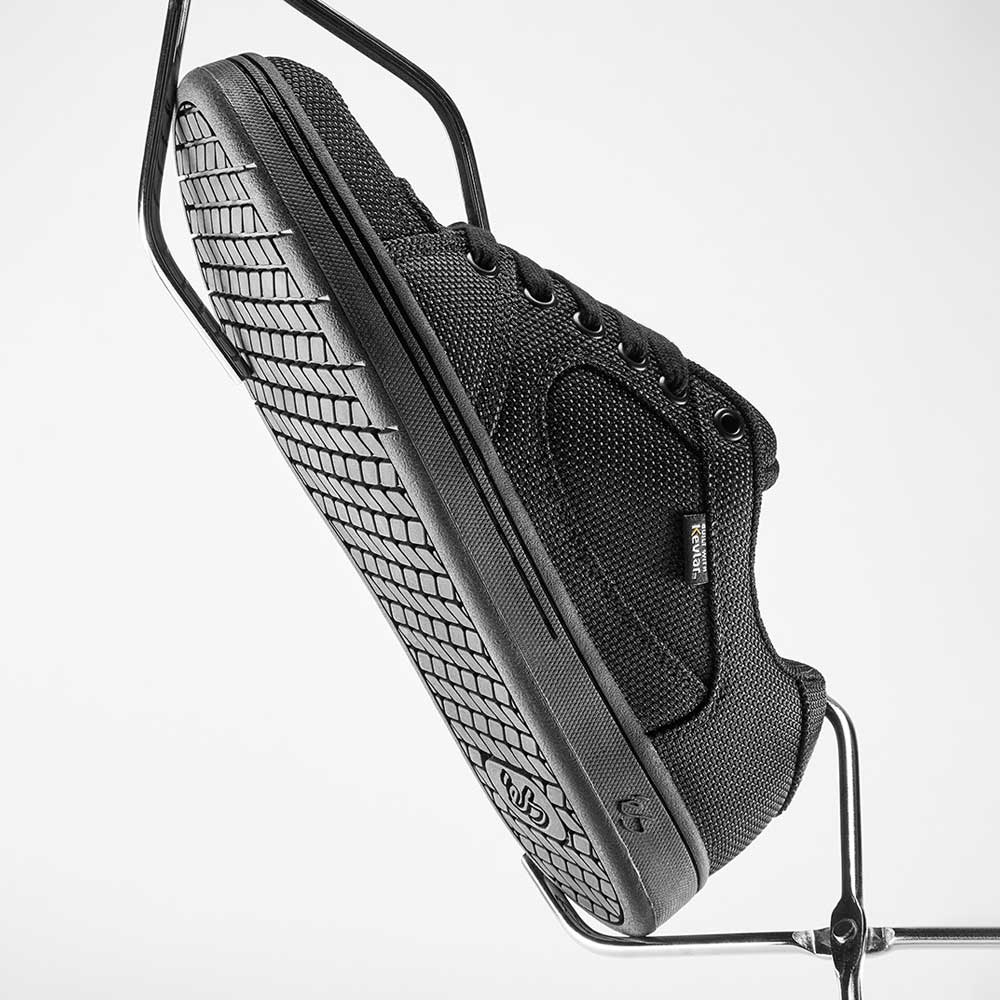 Accel Kevlar Black Es Shoes Skateboarding with textured sole, black laces, mesh panels, and a side logo tag shown at an angle on a metal stand against a white background—ideal for skateboarding.