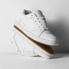 A pair of Accel White Leather Es Shoes Skateboarding with gum soles are stacked against a white background—one upright, the other sideways displaying the textured sole—ideal for those who love classic skate style.
