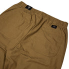 Close-up of the back of the Vans Addison Barrel Olive Brown VN0010HYOVB pants, featuring an elastic waistband and two large square pockets. These olive brown pants are designed in a loose-fit denim style reminiscent of classic skate jeans, with a small Vans logo tag visible above the right pocket.