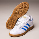 A pair of Busenitz Blue White Gum IE3101 Adidas Skateboarding leather shoes, featuring a white upper with blue stripes and gum soles. One shoe stands upright while the other is positioned to display its textured sole pattern. Gold Samba branding adorns the side, blending classic style with durable skate-inspired construction from Adidas.