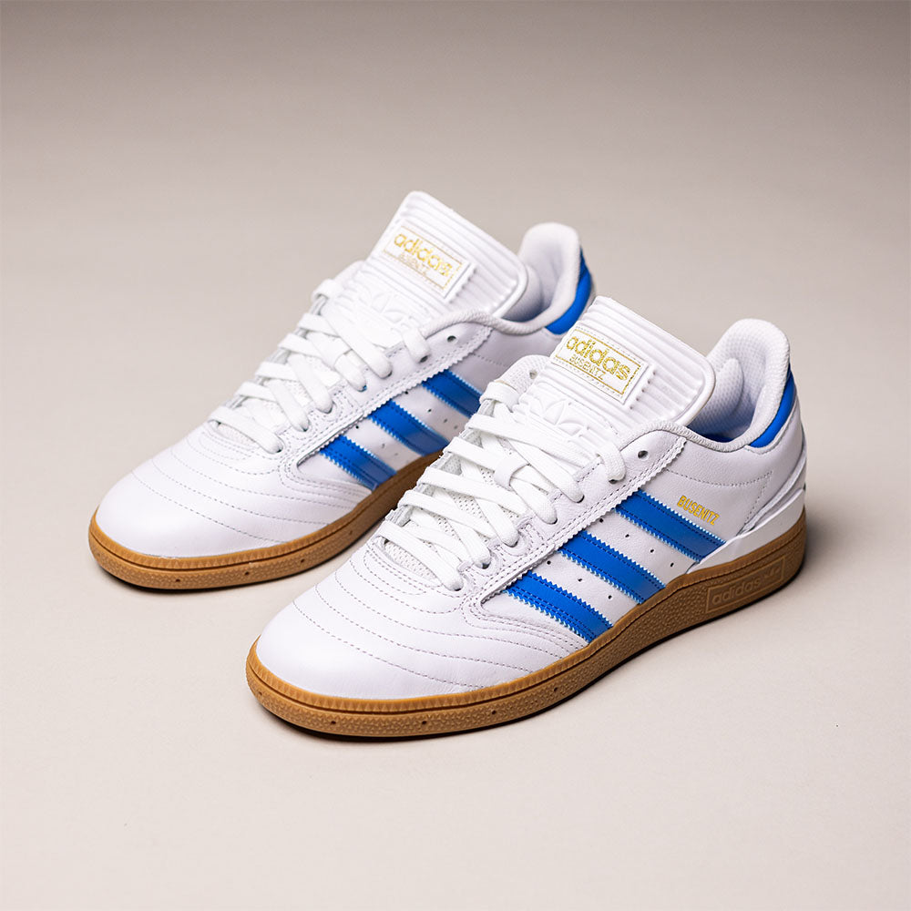 The Busenitz Blue White Gum IE3101 Adidas Skateboarding leather shoes—featuring white uppers with blue stripes, gold "MUNICH" text, white laces, and gum soles reminiscent of classic Busenitz style—are displayed on a plain light background.
