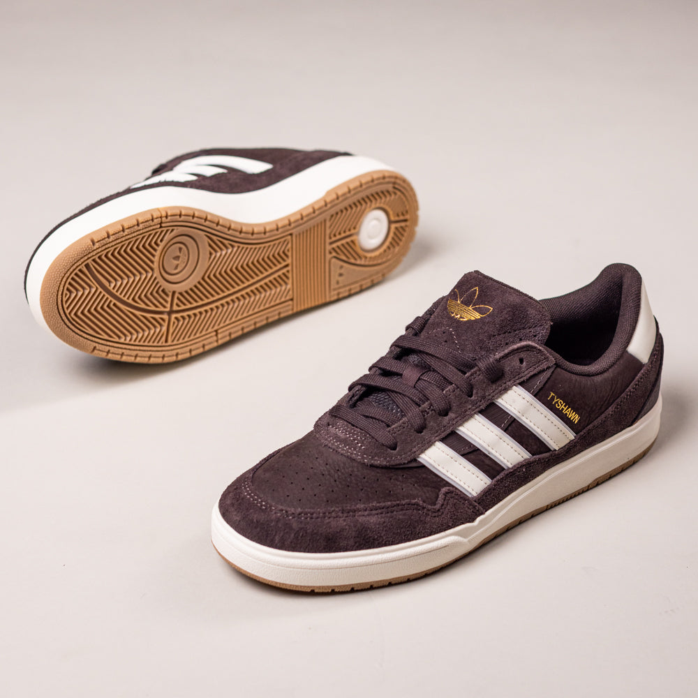 A pair of Tyshawn 2 II Brown White HQ4735 Adidas skateboarding shoes is displayed—one upright showing classic stripes and gold branding, the other revealing the gum sole.