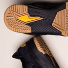 Close-up of the soles of KJ5054 Cordura Carbon Black Tekkira Cup Adidas Skateboarding Suede Shoes, featuring gum and yellow accents, textured grip patterns, and adidas “TORSION SYSTEM” technology on the bottom.