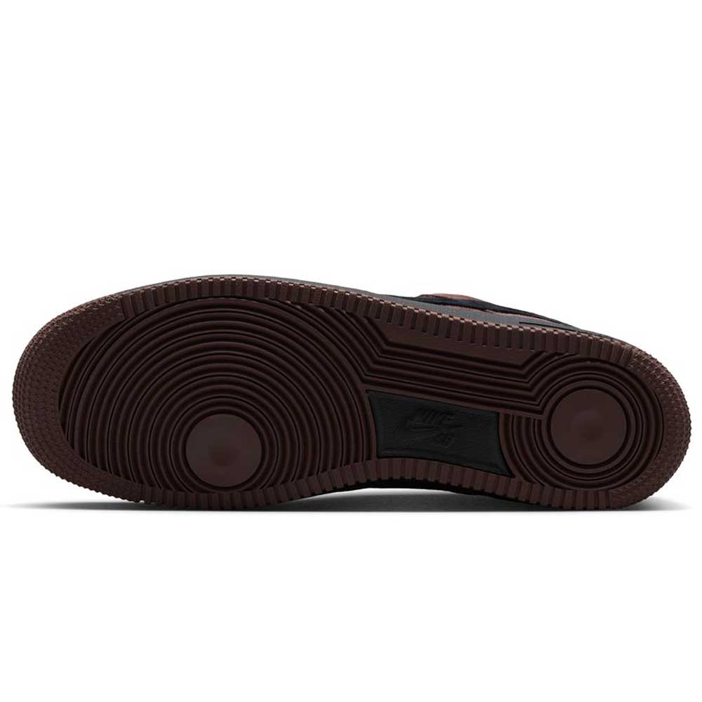 The image displays the brown rubber outsole of the Air Force 1 Black Light Chocolate HM8517201 Nike SB Suede Skateboarding Shoes, featuring circular traction patterns and a centrally embossed Nike logo. Engineered specifically for skateboarding, this durable and stylish outsole offers superior grip and support, complemented by the signature Nike Air cushioning for enhanced comfort during wear.