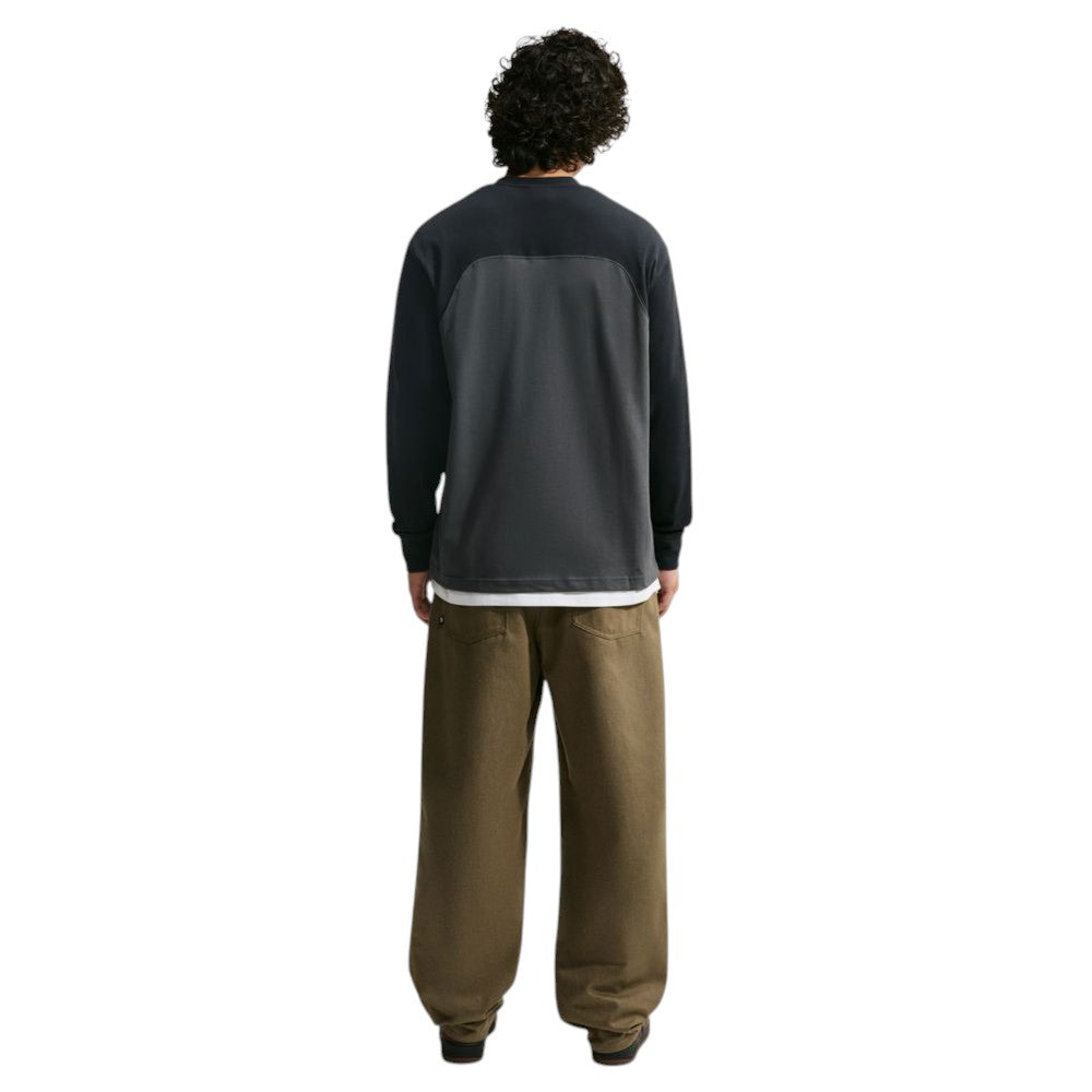 Back view of a person wearing a Nike SB Airmail Longsleeve IM5430060 Black Gray Skate Longsleeve T-Shirt over a white undershirt with baggy brown pants, offering durable comfort.