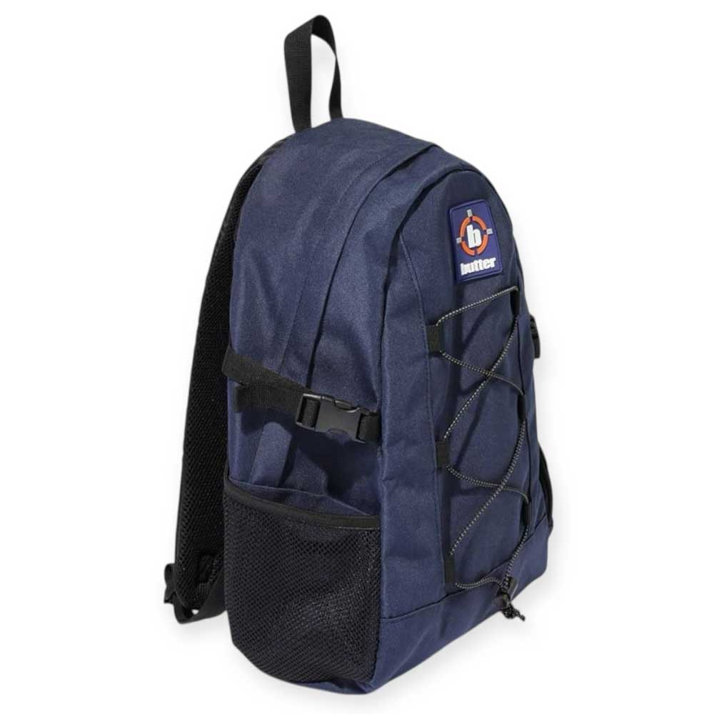 The Aleka Backpack Navy Butter Goods is a dark blue nylon canvas bag with black adjustable straps, mesh side pocket, front bungee cord, and a "hunter" logo patch on top. It offers a 40L capacity for all your essentials.