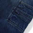 Close-up of Aleka Dark Indigo Denim Jeans by Butter Goods, showcasing a blue zipper and an embroidered circular logo with a stylized D near the zipper—crafted in classic loose fit style.