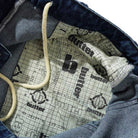 Close-up of Aleka Dark Indigo Denim Jeans Butter Goods, featuring a printed fabric lining with "butter" and repeating b logo over a grid, plus white drawstring and carpenter pocket stitching.
