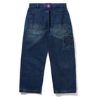 The Aleka Dark Indigo Denim Jeans by Butter Goods are loose fit cotton jeans with large carpenter pockets, a right-side utility loop, and a purple belt featuring a circular red and blue buckle, shown laid flat on a white background.