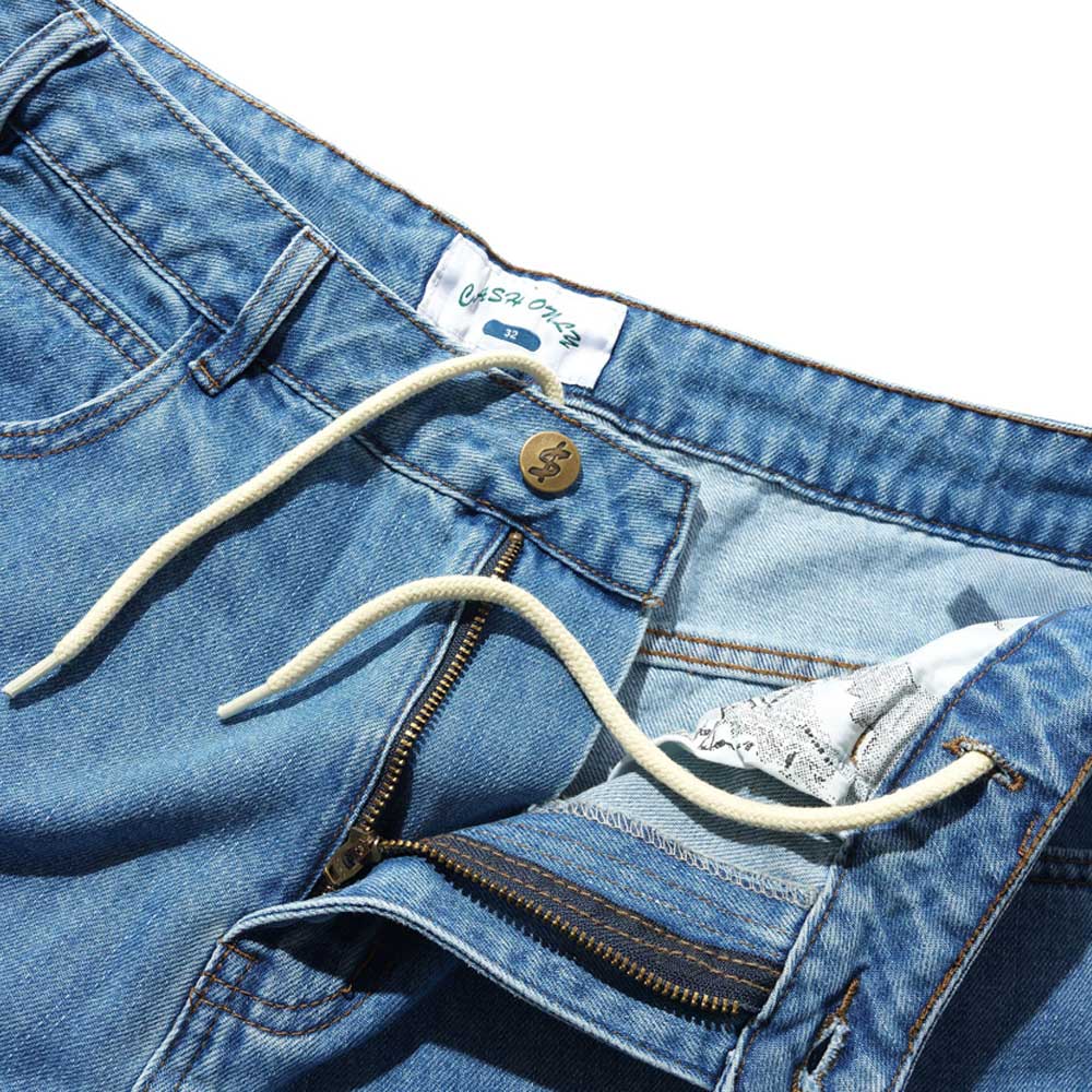 A close-up of Aleka Denim Jeans Distressed Mid Blue Cash Only COD153201, showing a white drawstring at the waistband, metal button, partially open zipper, and inner label.