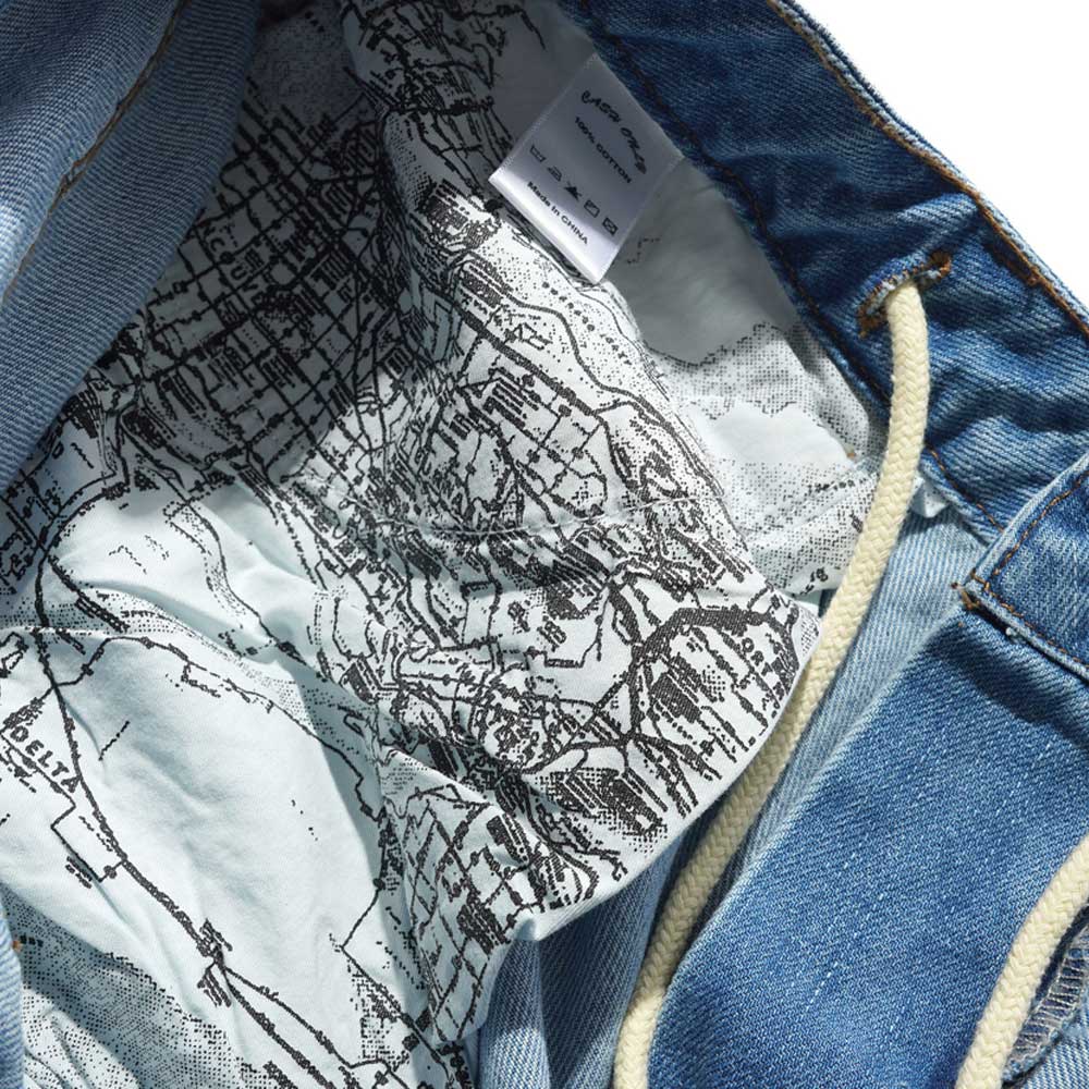 The inside of Aleka Denim Jeans Distressed Mid Blue Cash Only COD153201 features a white lining with a black map print and a white fabric tag sewn into the waistband above the map design.