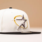 A White Black Circle Star Houston Astros New Era 5950 Fitted hat with a black brim and embroidered gold and silver star on the front, photographed against a light beige background.