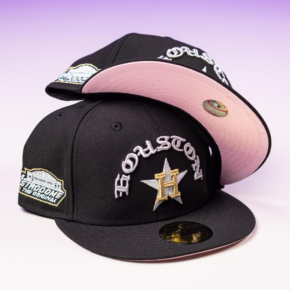 Two black Summer Nights Trilogy Houston Astros New Era 5950 Fitted caps are stacked; both show a silver and yellow H star, Houston text, side patch, gold brim sticker, and the lower cap features a pink undervisor.