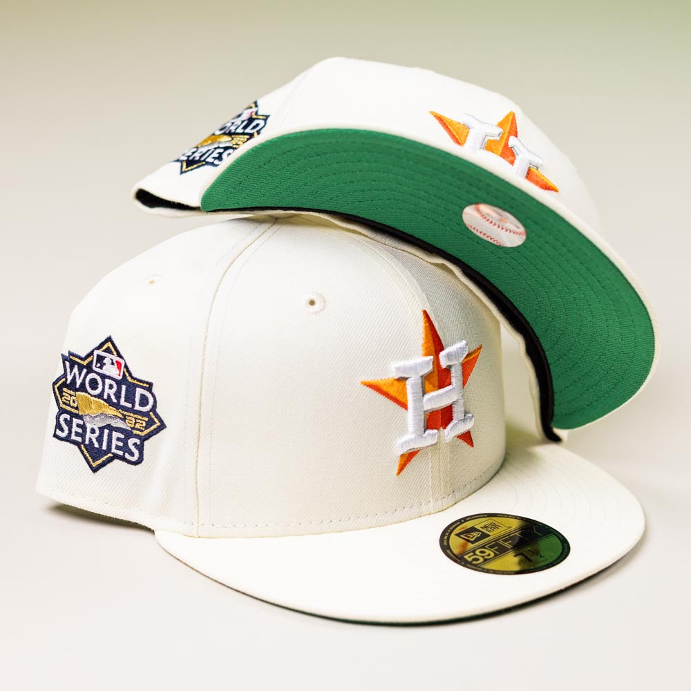 Two Summer Days 2022 Houston Astros New Era Hat 5950 Day caps in cream, with orange star H logos, a 2022 World Series patch, and green underbill, are stacked on a neutral background.