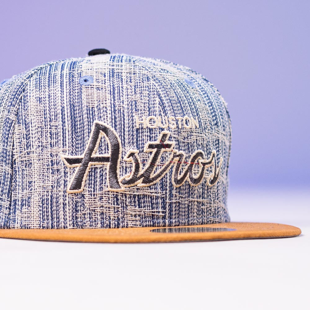 A Bronze Denim Houston Astros 5950 Fitted Hat by New Era, featuring 50th anniversary details and script "Astros" embroidery on the front, with a stylish design that makes this cap stand out.