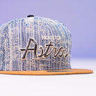 A Bronze Denim Houston Astros 5950 Fitted Hat by New Era, featuring 50th anniversary details and script "Astros" embroidery on the front, with a stylish design that makes this cap stand out.