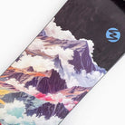 A close-up of the Atmosphere Switchblade 40 Landyachtz Complete Skateboard, showcasing a vibrant mountain landscape and clouds graphic with a blue stylized S logo near the top right, similar to designs seen on freeride longboards.